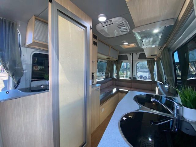 Three berth motorhome kitchen, bathroom door and rear lounge
